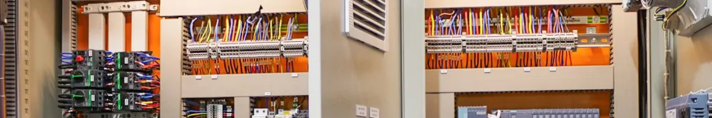 Open control panels with rows of terminal blocks, relays and coloured wiring.
