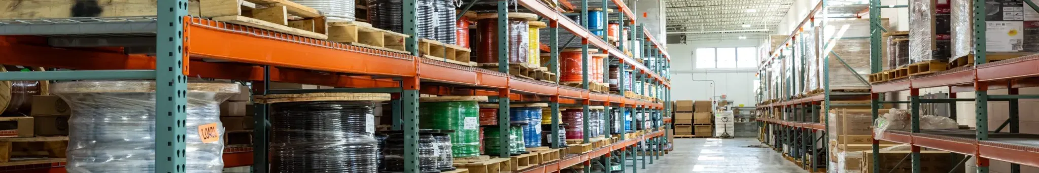 Reels of building wire in many colours on warehouse racking.